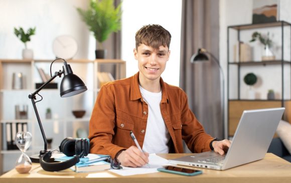 student z laptopem przy biurku